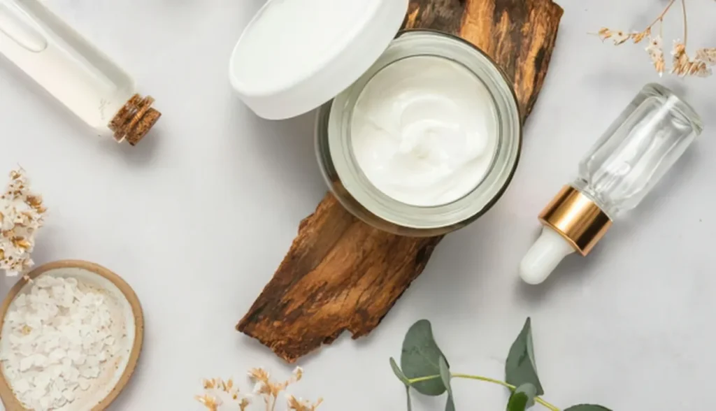 Natural skincare products including a cream jar, serum bottles, and botanicals, representing the cosmetics industry.