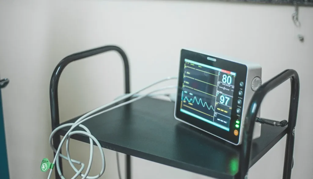Patient vital signs monitor placed on a trolley, representing difficulties tracking mobile clinical medical devices in hospitals.