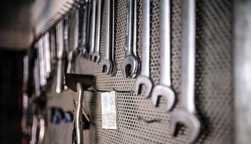 Metal wrenches neatly hung on a perforated metal workshop wall, professional hand‑tool storage in an industrial maintenance space.